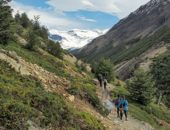 Rear view of people walking on mountain against sky