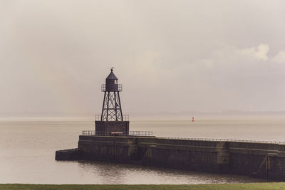 Lighthouse by sea against sky