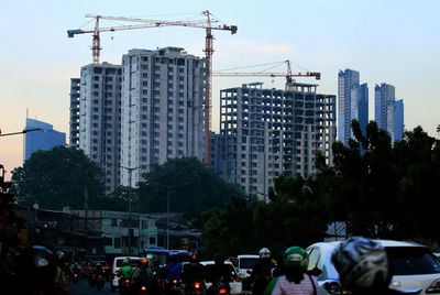 Cars on street by buildings in city against sky