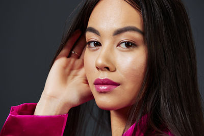 Close-up portrait of young woman against black background