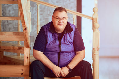 Portrait of young man sitting on wood