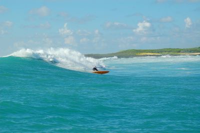 Person surfing in sea against sky