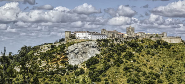 Panoramic view of buildings against cloudy sky