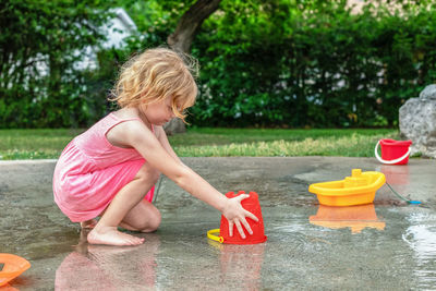 Small beautiful girl playing at fountain playground or splash pad 