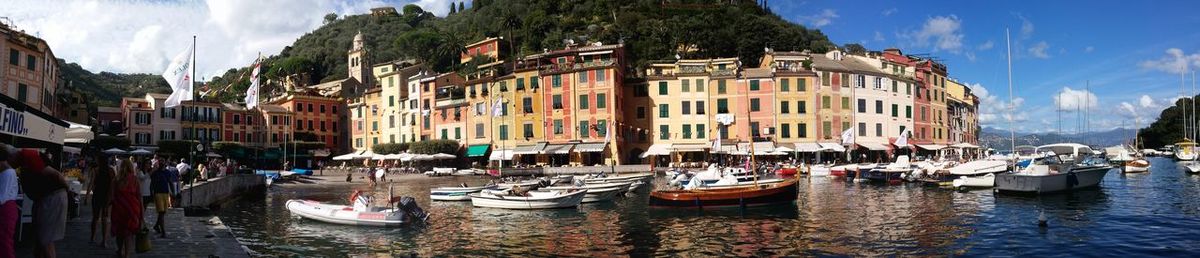 Panoramic view of boats moored in water against sky