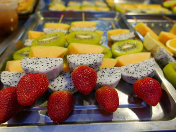 Close-up of fruits on skewers over tray at market stall