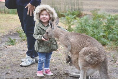 Close-up of girl holding dog in field