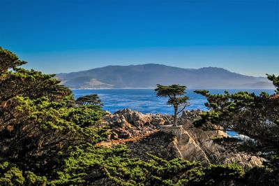 Scenic view of sea and mountains against blue sky