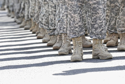 Low section of men in military uniform standing on street during sunny day