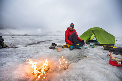 Mountaineer enjoys moving campfire on glacier in the artic.