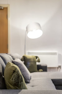 Close-up of illuminated electric lamp on bed at home