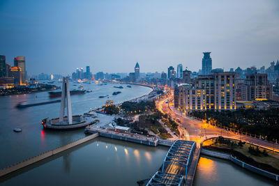 High angle view of illuminated city by river against sky