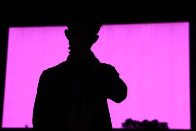 Silhouette of man standing against pink light