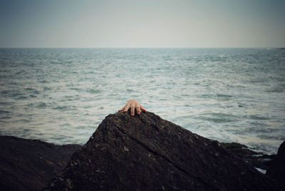 Scenic view of creepy hand against clear sea