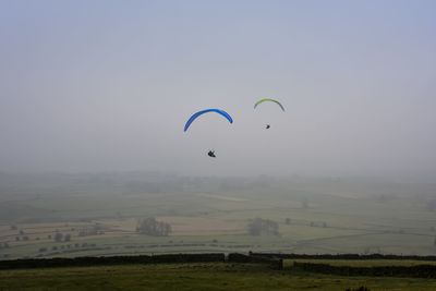 Kite flying over field against sky