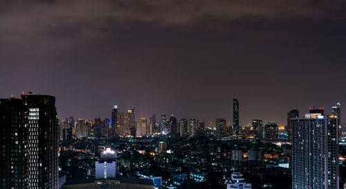 Illuminated buildings in city against sky at night