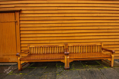 Empty bench against yellow wall