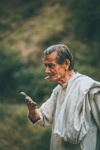 Senior man smoking cigarette while gesturing with dirty hands