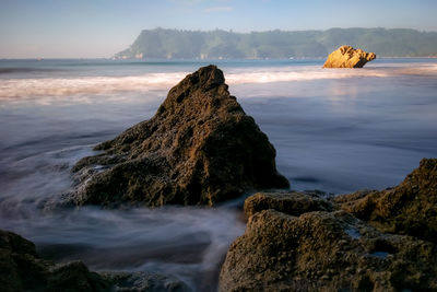 Scenic view of rocks on beach against sky