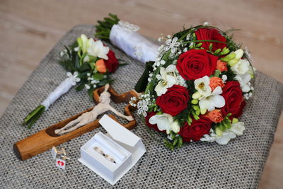 High angle view of bouquet and wedding rings on chair