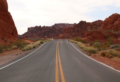 Road leading towards mountains against sky