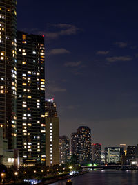 Illuminated modern buildings against sky at night