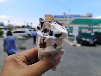 Hand holding ice cream cone on street