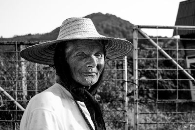Portrait of woman wearing hat against fence