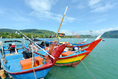 Boats moored in sea against blue sky