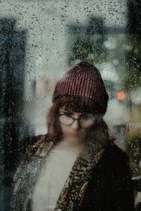 Reflection of young woman on wet glass window