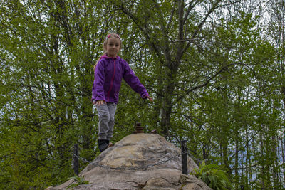 Full length of boy standing on rock in forest