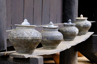 Close-up of old pots on table against wall