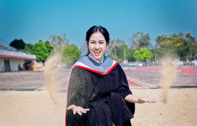 Portrait of smiling young woman standing against sky