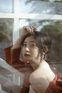 Portrait of young woman looking through window