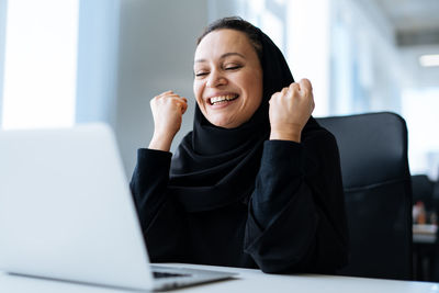 Young woman using laptop while sitting on table