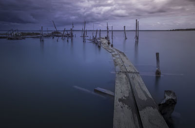 Wooden posts in sea against sky