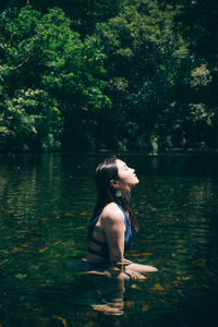 Side view of woman sitting in lake