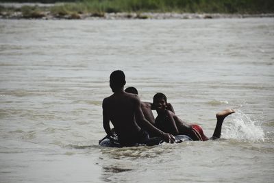 Rear view of men sitting on beach