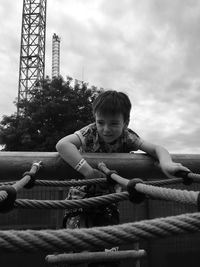 Boy playing climbing on jungle gym against sky