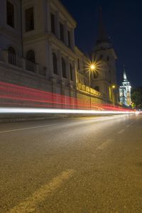 Light trails on street against illuminated buildings at night