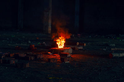 Lighting a fire on stone at night. small red fire, smoke from flames, scattered firewood.