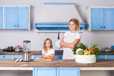 Portrait of smiling mother with daughter at kitchen