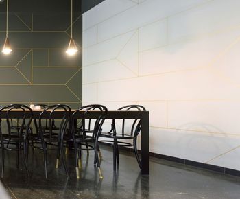 Empty chairs and table against illuminated wall at home