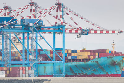 Cranes at harbor against sky