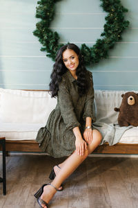 Photo of a positive lady sitting on a cozy sofa in a house indoors with a christmas 