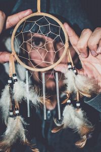 High angle portrait of young man looking through dreamcatcher