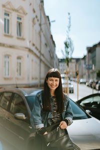 Portrait of smiling woman standing by car