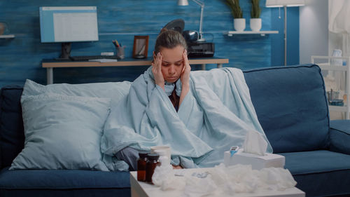 Young woman using mobile phone while sitting on bed at home