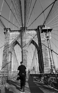 Rear view of man walking on suspension bridge