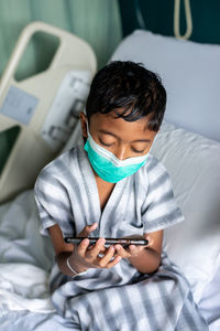 Boy using mobile phone on bed